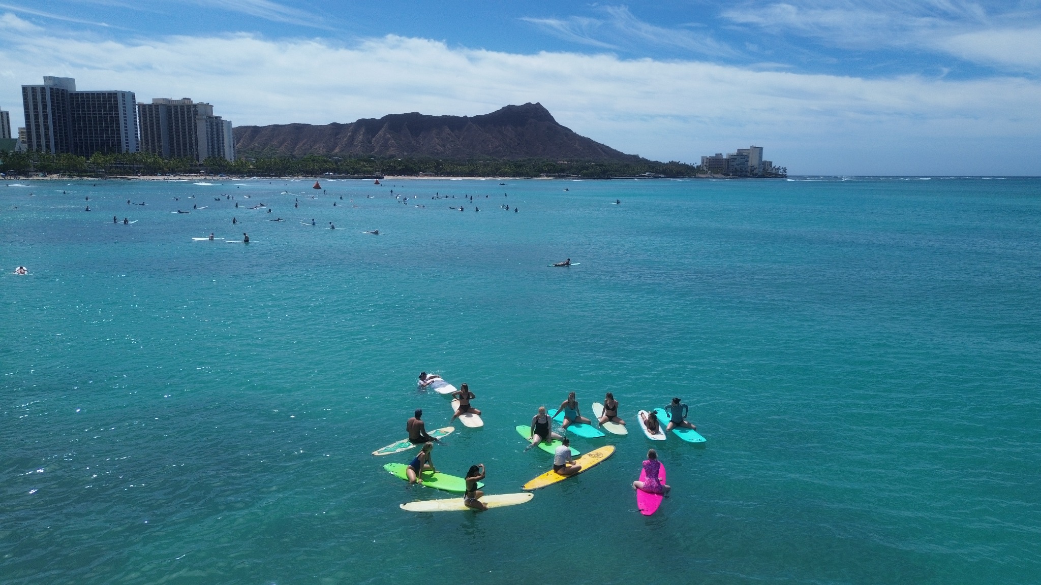 HI Surf Camp group training in clear Waikiki water with Diamond Head behind them